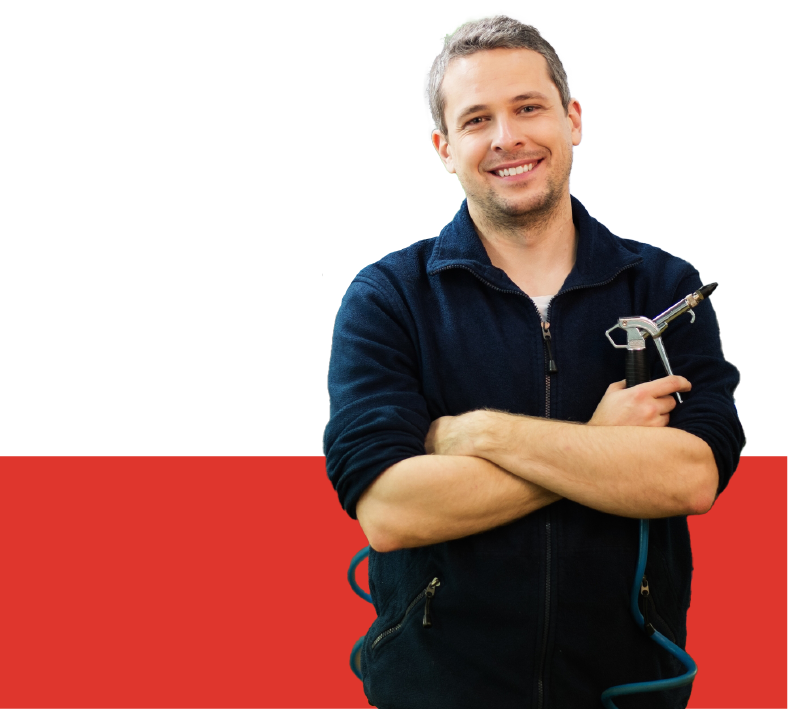 A full shot of a smilling auto mechanic on a blue jacket holding a tool on his hand.